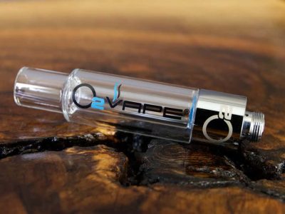 A single uncapped All Glass 510 Vape Cartridge is horizontally laid across a warm wood surface. The O2VAPE logo is visible on the glass body.