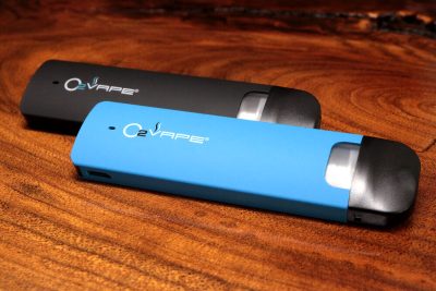 2 Traveler Extreme ® Vari-Vape Pens are displayed horizontally at an angle. The pen in the back is black, with the blue pen in front. The O2VAPE logo is displayed on the body of both pens.