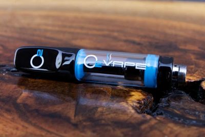 1 black Full Ceramic Vape Cartridge is horizontally displayed here against a warm wood surface . The O2 logo is on the black mouthpiece. The O2VAPE logo is displayed on the clear body.