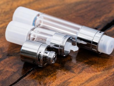 2 white All Glass Vari-Flow Vape Cartridges are displayed horizontally at an angle. The longer 1ml cartridge at the top and the shorter .5ml cartridge is beneath. The .5ml cartridge is open.